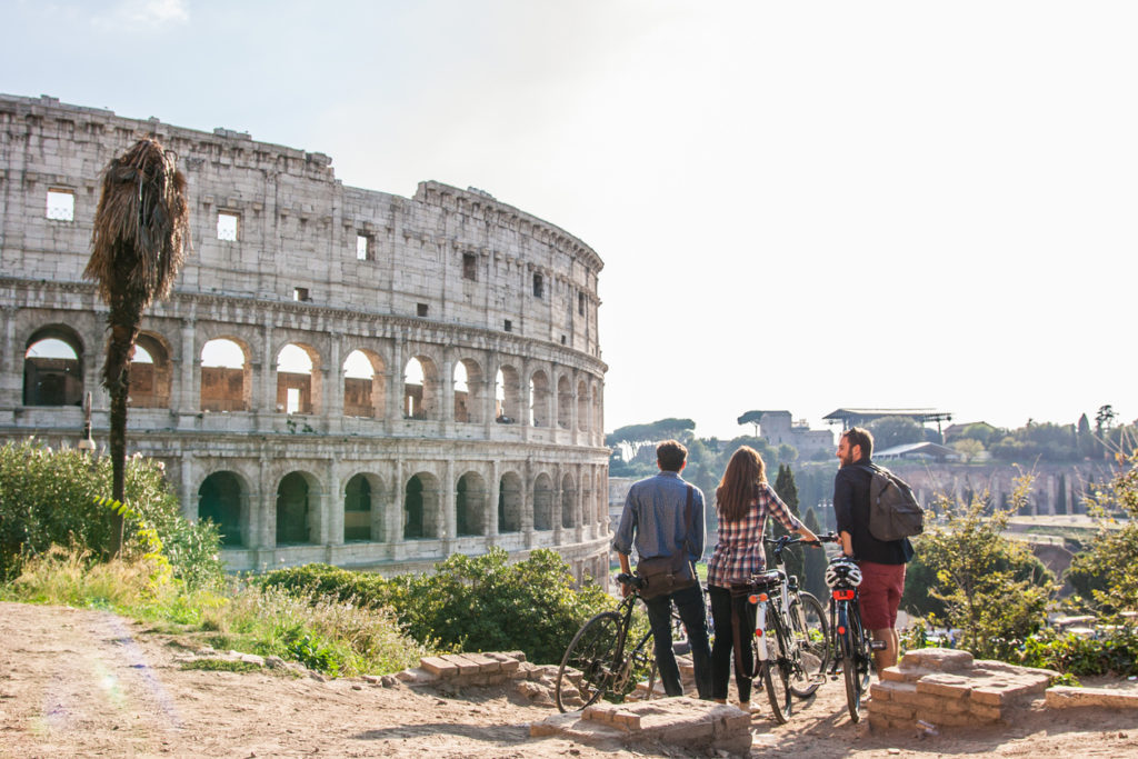 Drei Freunde mit Fahrrädern vor dem Kolosseum in Rom, Italien