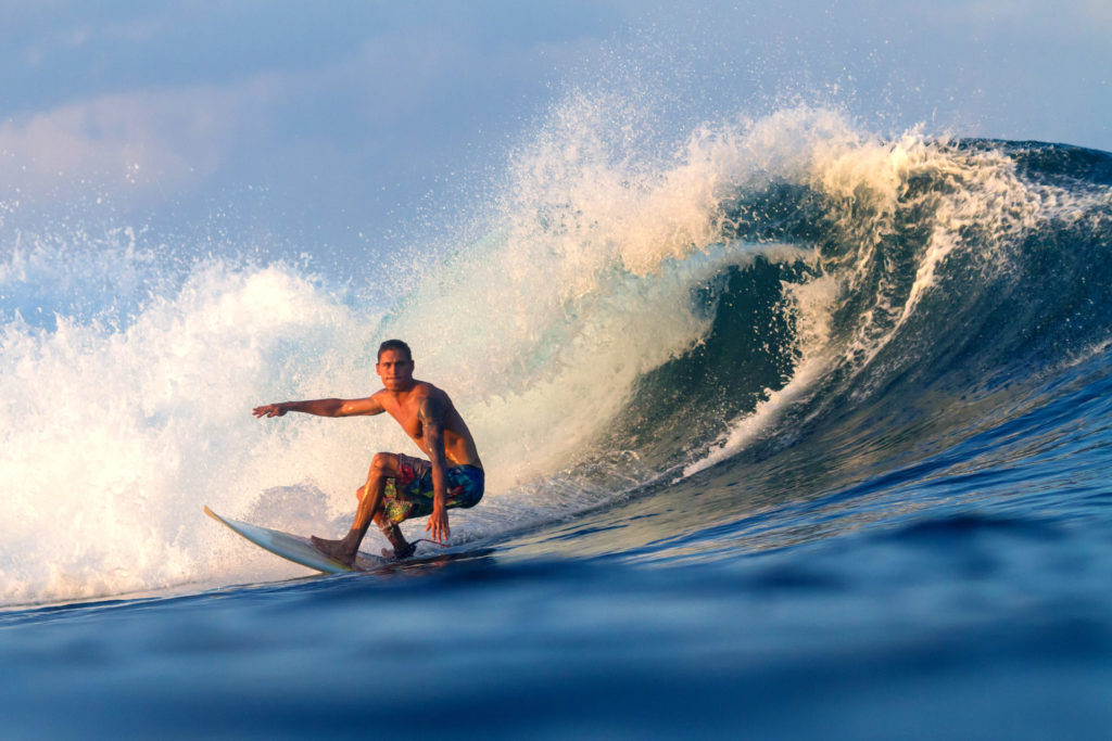 Surfer reitet eine Welle bei Sonnenuntergang