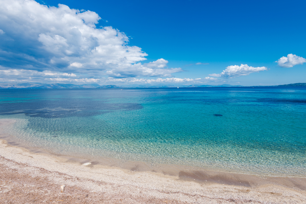 Agios Ioannis Peristeron Strand mit lauem und türkisfarbenem Wasser, vereinzelte Wolken am Horizont