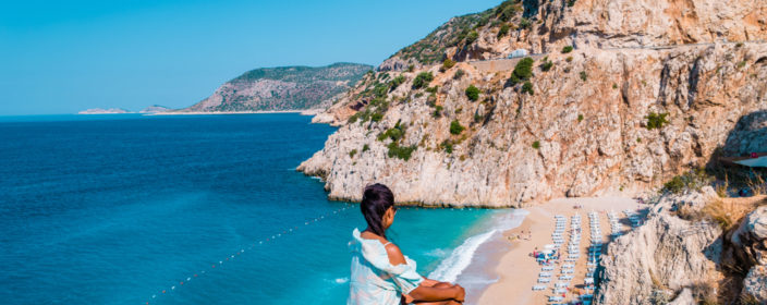 Junge Frau auf einem Felsen oberhalb des Kaputas Strand an der türkischen Riviera