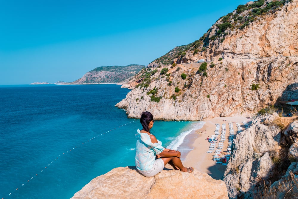 Junge Frau auf einem Felsen oberhalb des Kaputas Strand an der türkischen Riviera
