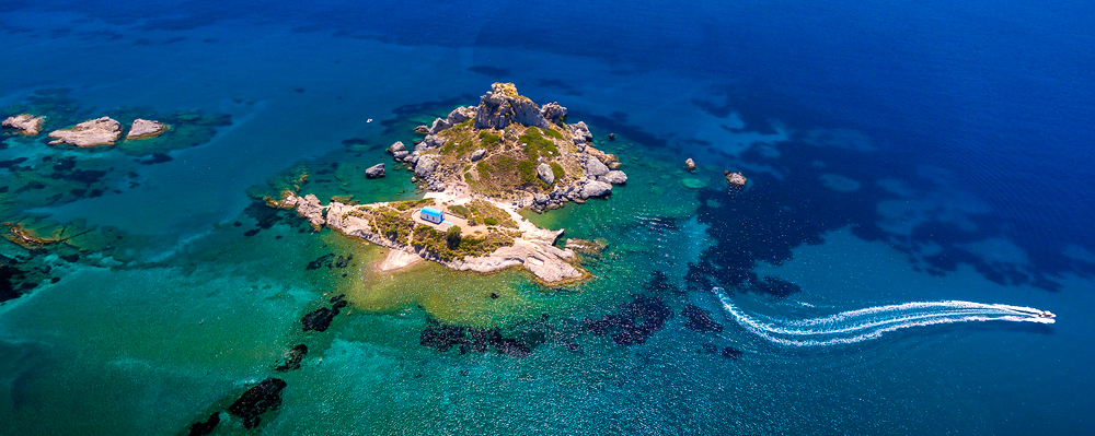 Kastri Insel im Dorf Kefalos mit einer kleinen Kapelle, umgeben von grün-blauem Meerwasser mit