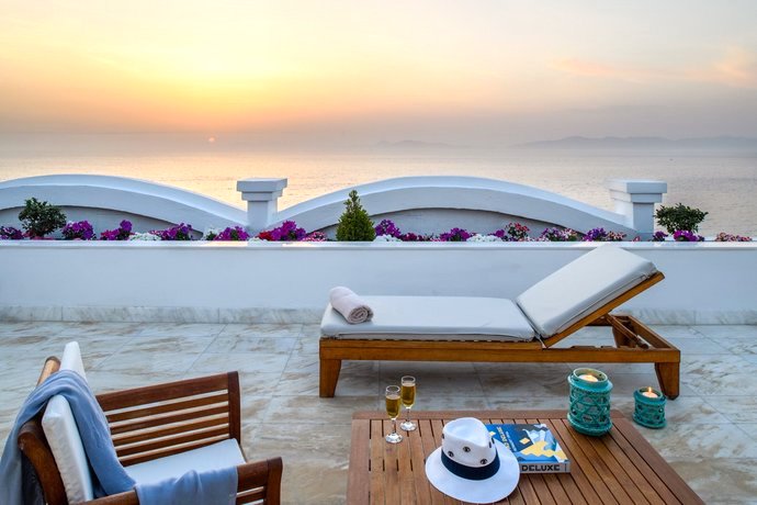 Terrasse es Mitsis Grand Hotel Beach Hotel mit Sonnenliege und Champagnergläsern bei Sonnenuntergang