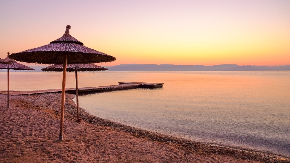 Sonnenuntergang am Moraitika Strand auf Korfu mit Sonnenschirmen und ruhiger See