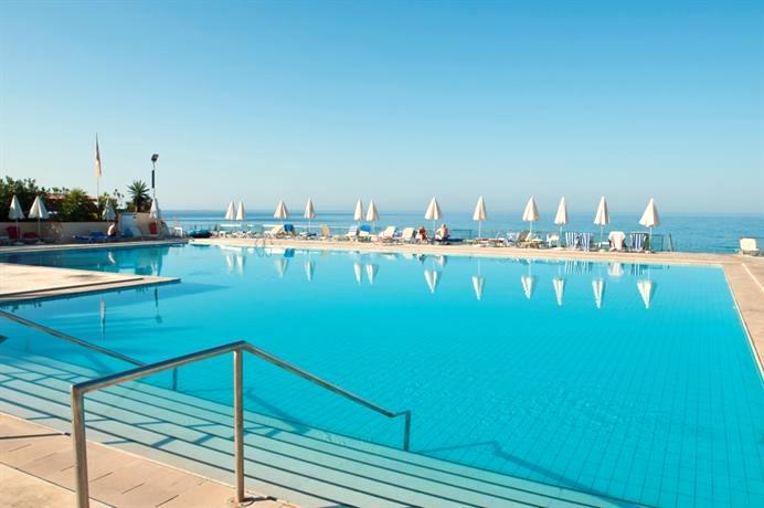 Pool mit Sonnenschirmen im LTI Louis Grand Hotel mit Meer im Hintergrund