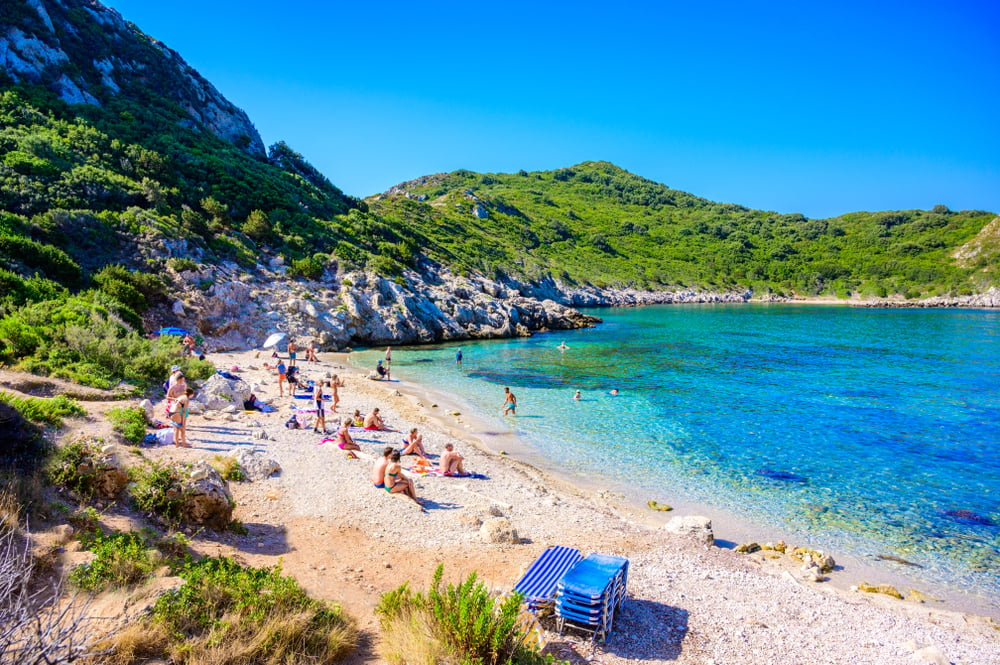 Porto Timoni Strand auf Korfu mit einigen Badegästen und grünem Hügel im Hintergrund