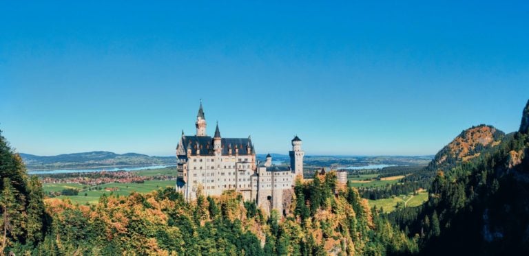 Schloss Neuschwanstein umgeben von Nadelwald und grüner Landschaft