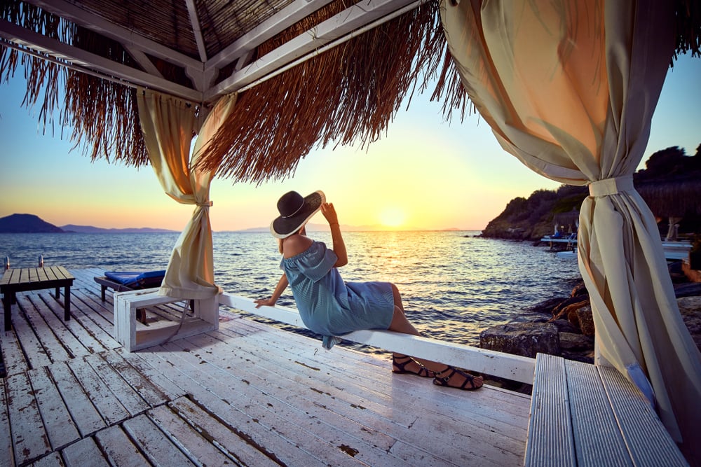 Frau mit Sonnenhut in einem Strandhotel in Bodrum bei Sonnenuntergang