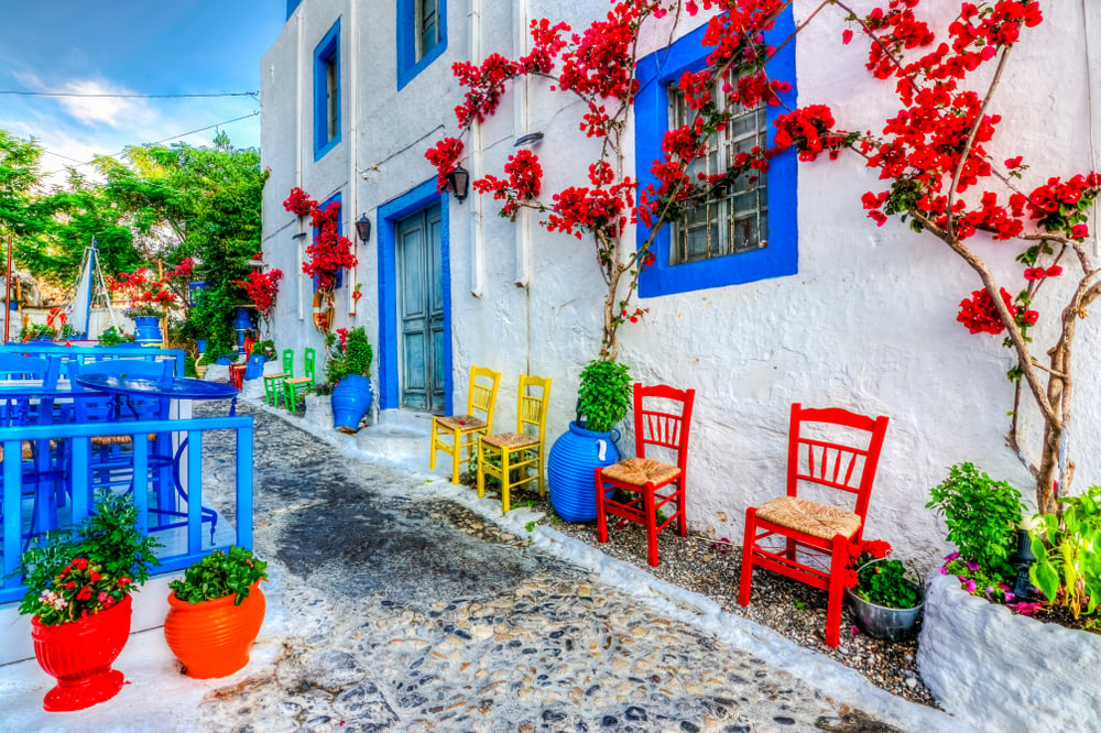 Typisches Haus auf Kos mit azurblauen Fensterrahmen, weißen Wänden und roten Blumen