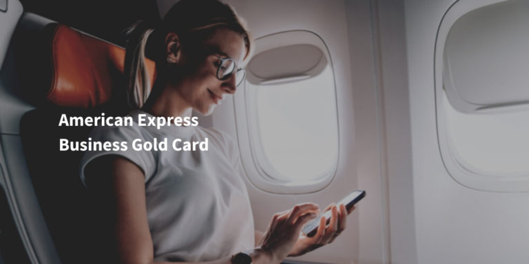 American Express Business Gold Card Schriftzug auf Bild mit junger Frau im Flugzeug, die ein Smartphone verwendet
