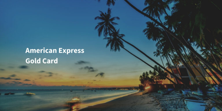 American Express Gold Card Schriftzug auf Bild mit Strand und Palmen bei Sonnenuntergang