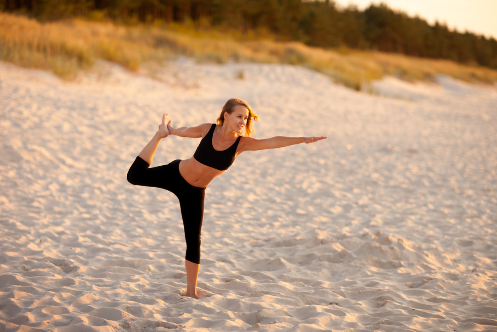 Frau macht Yogaübungen am Strand, Ostsee
