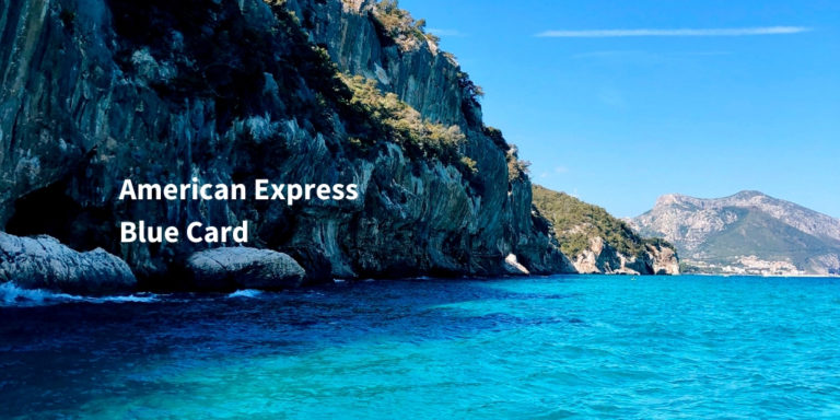 American Express Blue Card Infoseite Schriftzug auf Bild mit Felsen und blauem Wasser an der Küste von Sardinien
