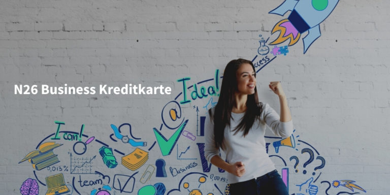 N26 Business Kreditkarte Schriftzug vor Wand mit kreativen Zeichnungen mit junger Frau, die eine Faust ballt und sich freut