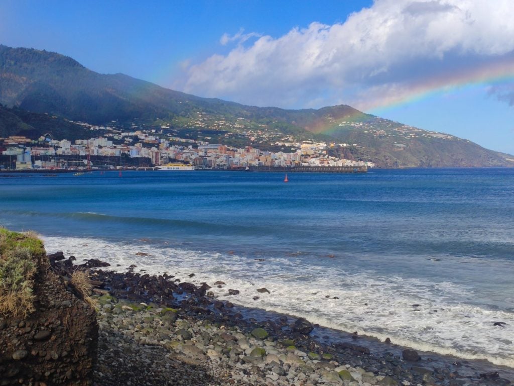 Die Hauptstadt Santa Cruz de La Palma vom Strand aus mit einem Regenbogen im Hintergrund