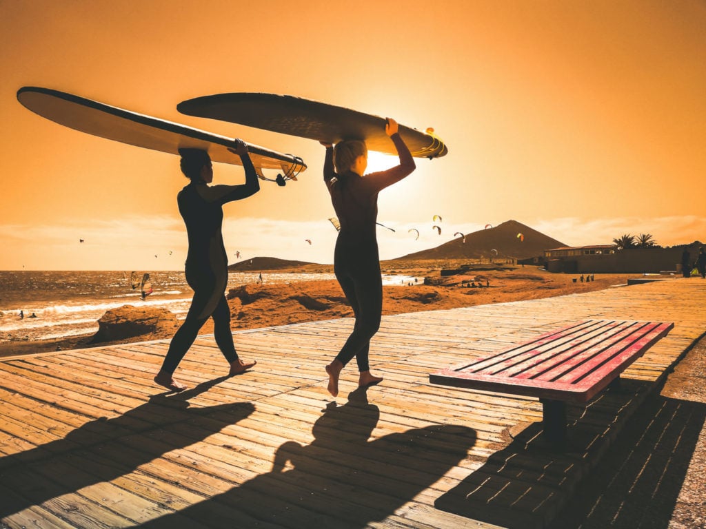 Zwei Frauen gehen surfen in El Medano, Teneriffa, Kanarische Inseln