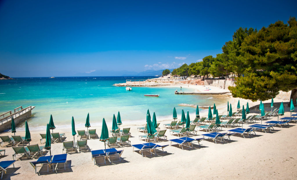 Sonnenschirme und Liegestühle am schönen Strand von Ksamil, Albanien.