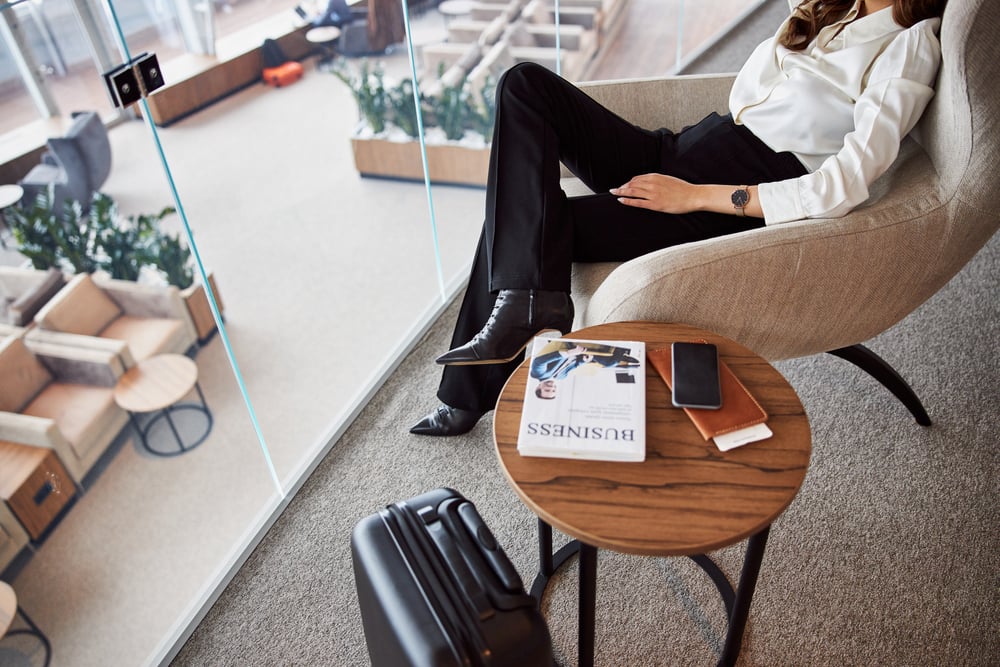 Stylische junge Frau auf komfortablem Stuhl in einer Business Airport Lounge