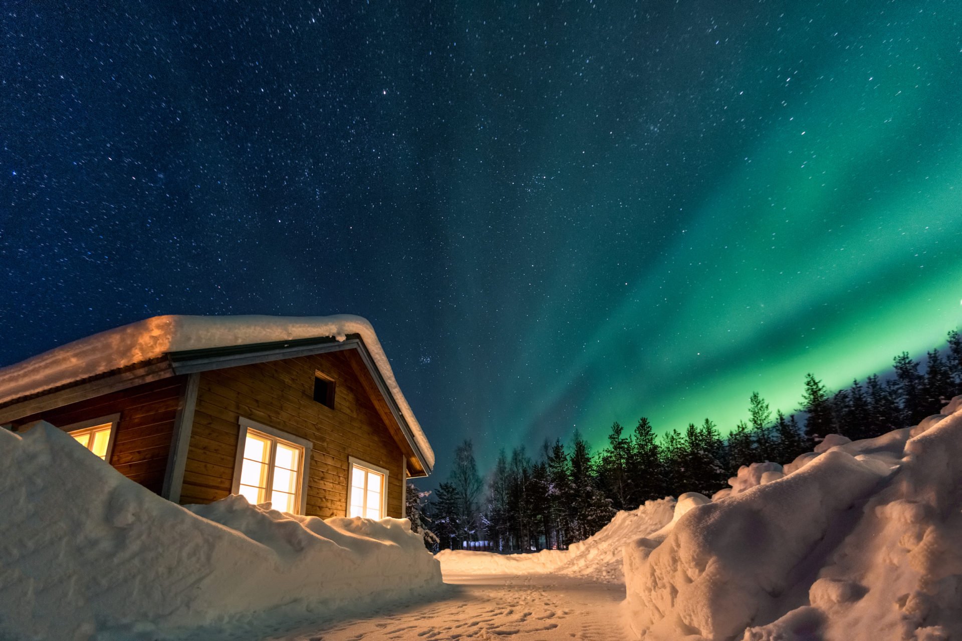 Holzhaus unter Nordlichtern in Schweden